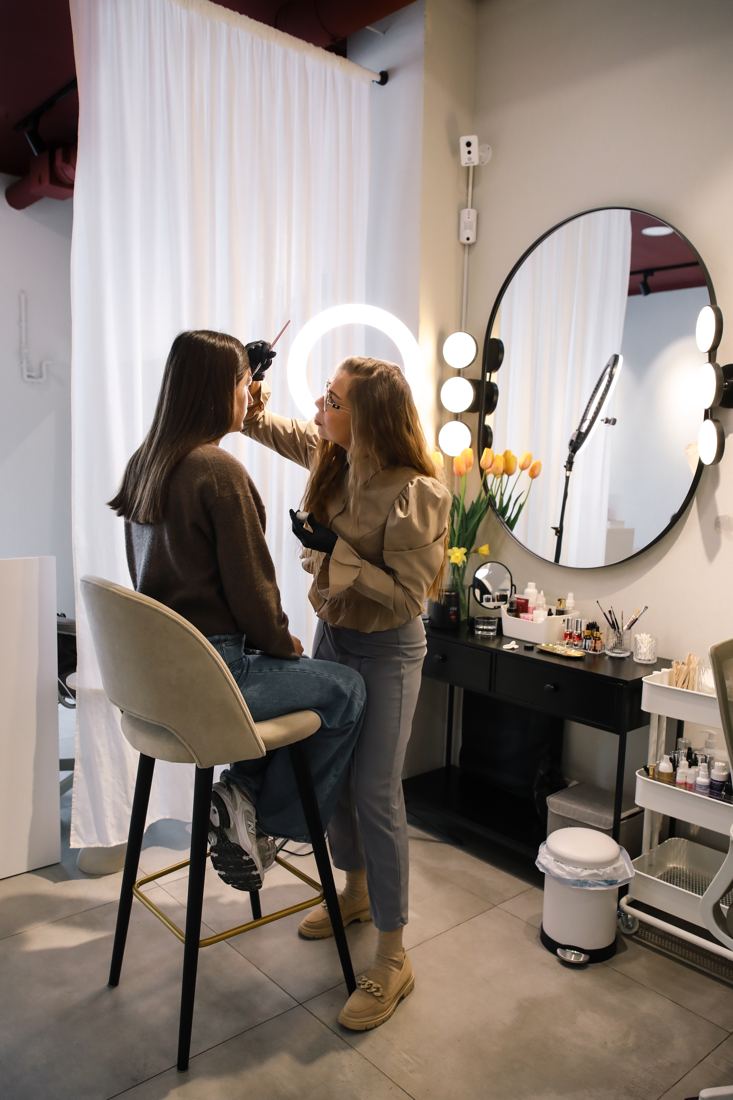 Майстриня робить корекцію брів біля дзеркала